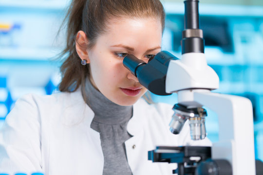 Young woman in biological laboratory. Attractive young female scientis. Scientist using a microscope in a laboratory