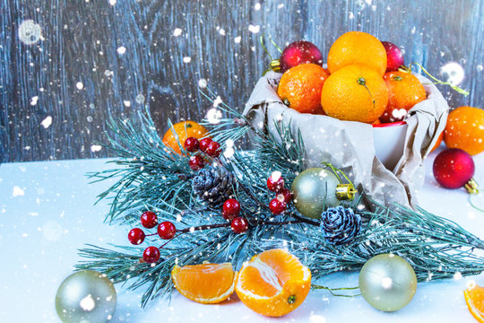 Christmas composition with tangerines, cinnamon and fir twigs in wooden plate on a festive table on a green background with snowflakes and cones fake.tinted