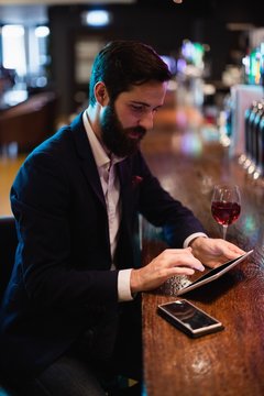 Businessman using digital tablet with wine glass and mobile phon