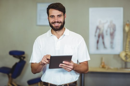 Male therapist holding digital tablet in clinic