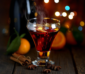 Mulled wine with spices and tangerines on wooden background