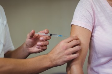 Male therapist injecting female patient