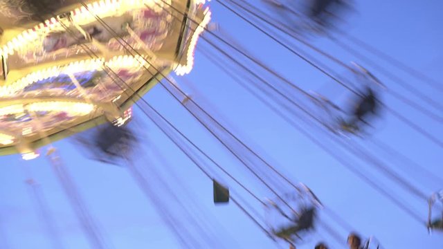 People riding swings during evening hours at carnival.
