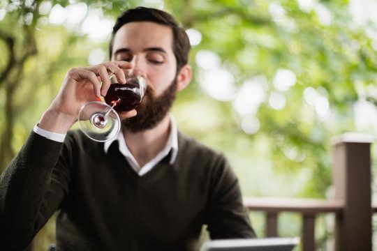 Man using digital tablet while having glass of wine