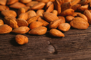 Apricot kernels are scattered on the wooden background