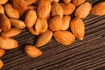 Apricot kernels are scattered on the wooden background