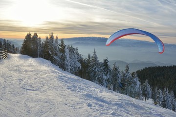 Paraglide silhouette over mountain peaks.