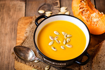 Bowl of pumpkin soup on rustic wooden background