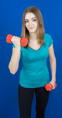 girl with dumpbells on blue background sport concept gym