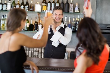 Two women toasting their glasses at bar counter