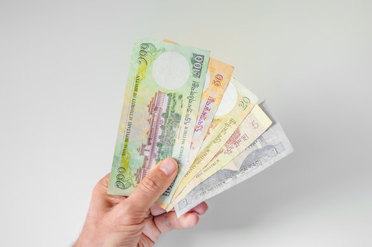 Man holding a bunch of Bhutanese Ngultrum banknotes in his hand