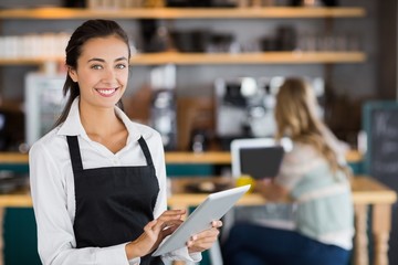 Portrait of smiling waitress using digital tablet - Powered by Adobe