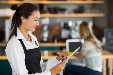 Smiling waitress using digital tablet