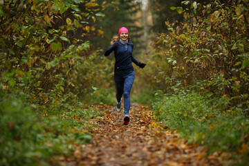 Fototapeta premium Young sportswoman running among trees