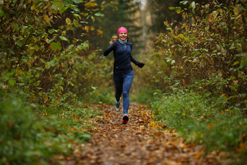 Young sportswoman running among trees