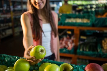 Fototapeta premium Woman selecting a green apple in organic section