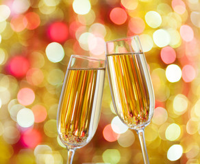 Two glasses of champagne against background with sparkles. Very shallow depth of field. Selective focus