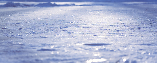 Blue panoramic ice surface covered with snow with selective focus as winter background during Christmas holidays