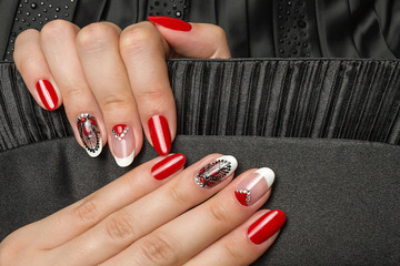 French manicure - beautiful manicured female hands with red black and white manicure with rhinestones  on black background