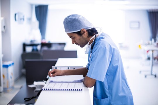 Side view of surgeon reading medical reports in hospital
