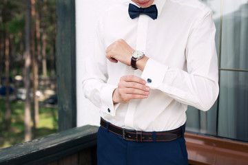 the man in a white shirt dresses cuff links on cuffs. Morning of the groom. Male clothes style