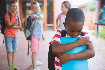 School friends bullying a sad boy in corridor - obrazy, fototapety, plakaty