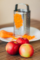 red apple and yellow carrots on the wooden table