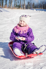 Fototapeta na wymiar little girl in bob-sleigh enjoying winter time