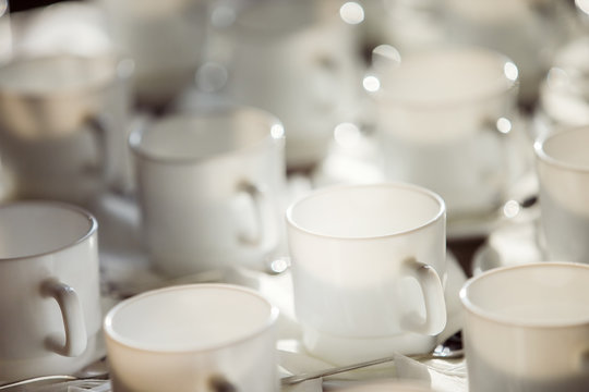 Closeup image of white cups at blurred table background.