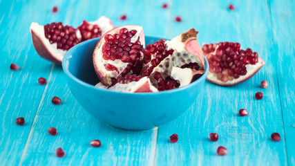 Chopped pomegranate in a bowl of blue on blue shabby wooden background