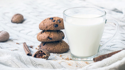 Oatmeal chocolate chip cookies and a glass of milk on a knitted beige background. Christmas treats. Shallow Selective focus.