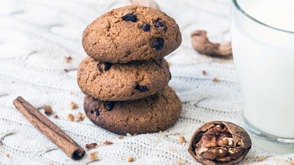 Oatmeal chocolate chip cookies and a glass of milk on a knitted beige background. Christmas treats. Shallow Selective focus.