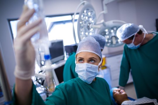 Female surgeon adjusting iv drip in operating room