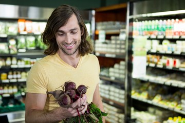 Man holding bunch of beetroots in supermarket