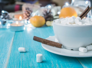 A cup of hot cocoa with marshmallows and sticks of cinnamon on a bright blue wooden background shabby. Shallow Selective focus.