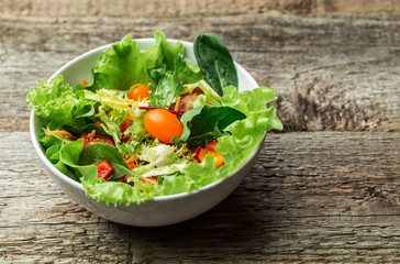 Salad with fresh vegetables - tomatoes, carrots, bell peppers and mixed greens - arugula, mesclun, mache.