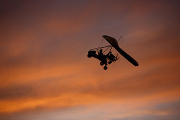 Hang-glider flying in red-pink sky