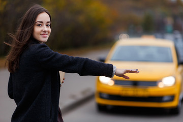 Smiling young woman tries to stop taxi