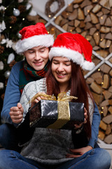 Smiling couple with gifts near Christmas pine