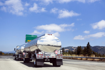 Shiny fuel truck on highway under blue sky. Horizontal.