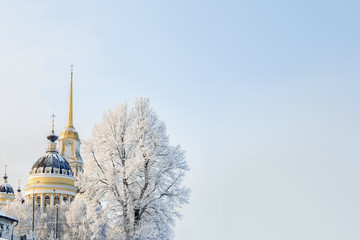 City landscape. Trees and buildings white with snow and frost on a cold, sunny day. Cathedral. Russia.