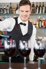 Waiter pouring wine into glasses