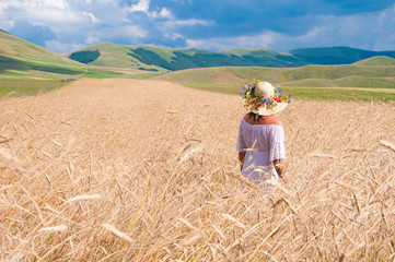 Naklejka na ściany i meble Girl wearing White dress in a wheat field
