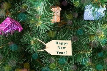 Gift boxes and tag with inscription "Happy New Year!" on christmas tree