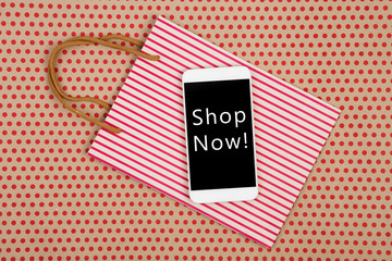 shopping bag and white smartphone with inscription "Shop Now!"