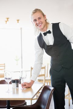 Waiter standing at table with empty glass