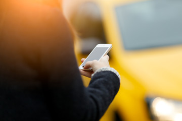 Brunette with phone against taxi