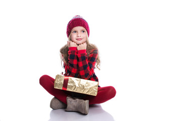 Cute smiling little girl with curly hairstyle wearing knitted sweater, scarf and hat holding christmas gift isolated on white background. Winter clothes and christmas concept.