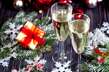 glasses of champagne and Christmas ornaments on dark wooden background