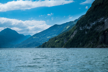 View acress the lake on a cloudy day with mountains in the backg